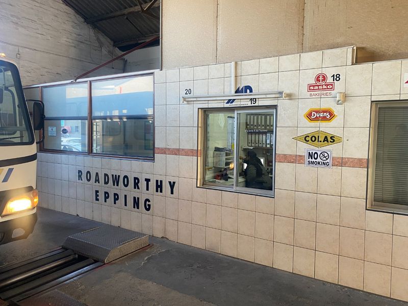 Industrial inspection office featuring tiled wall cladding and a service window within a large warehouse facility.