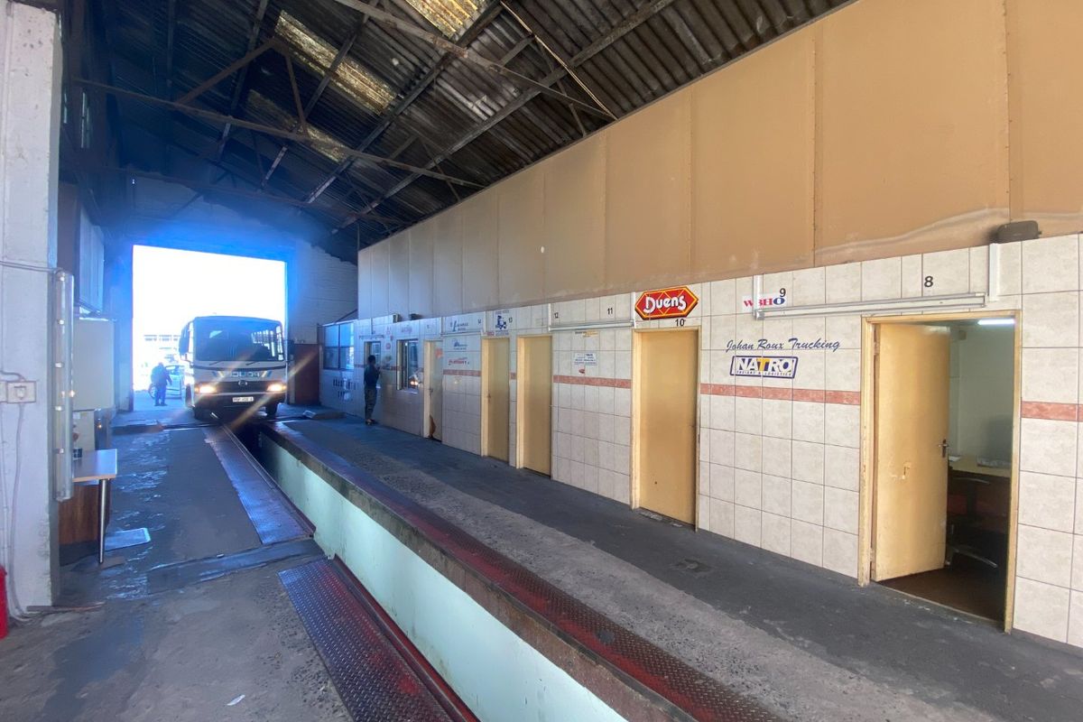 Industrial loading bay area featuring high ceilings, concrete flooring, and multiple access points to adjacent office spaces.