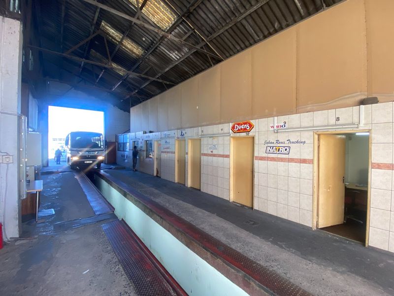 Industrial loading bay area featuring high ceilings, concrete flooring, and multiple access points to adjacent office spaces.