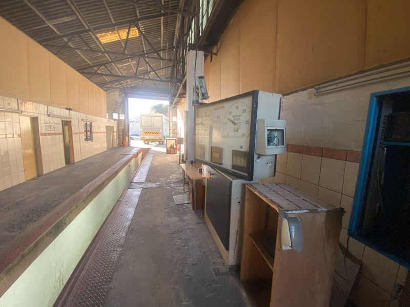 Industrial utility space featuring a braking force testing station, tiled wall finishes, and direct access to a loading dock area.