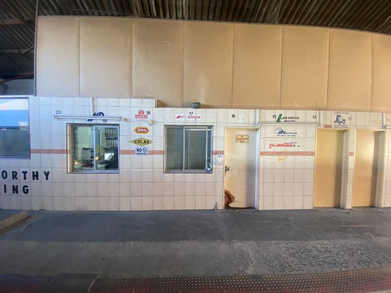 Industrial utility area featuring tiled wall partitions, service windows, and multiple access doors within a large warehouse-style structure.