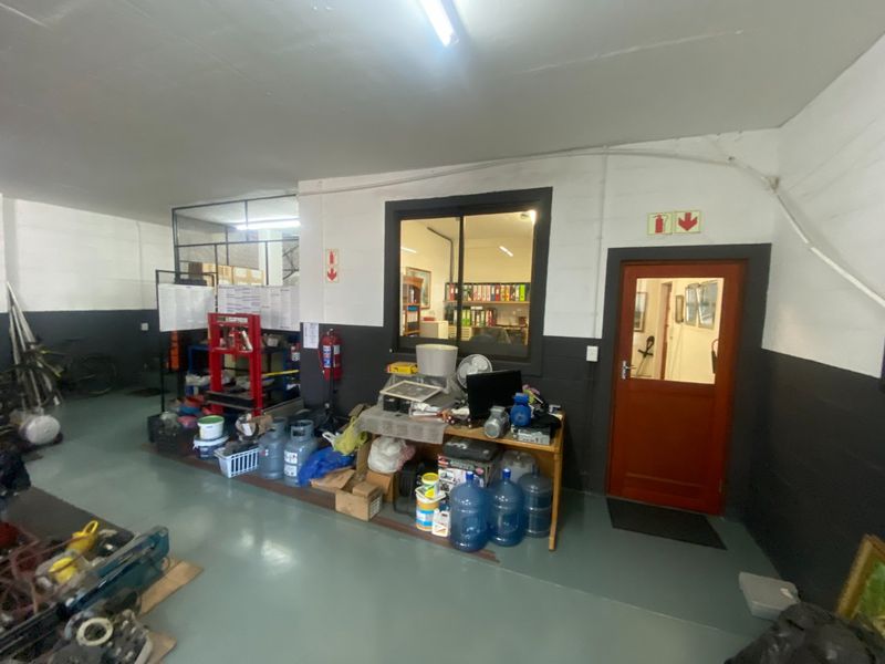 Industrial utility space featuring epoxy flooring, internal office window, and secure access door, suitable for workshop or storage operations.