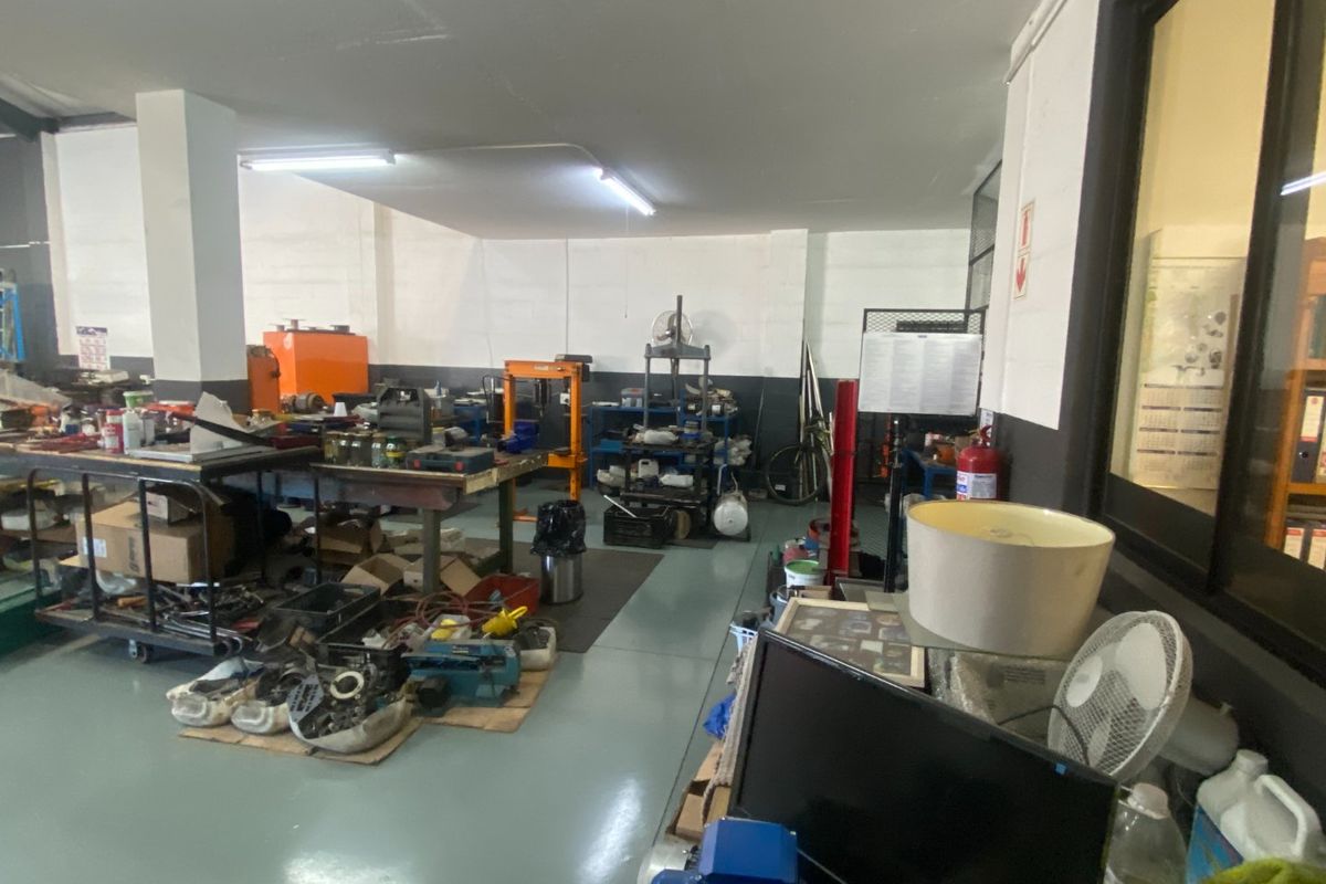 Industrial utility or workshop space featuring durable epoxy flooring, structural columns, and overhead fluorescent lighting, suitable for various commercial or industrial operations.