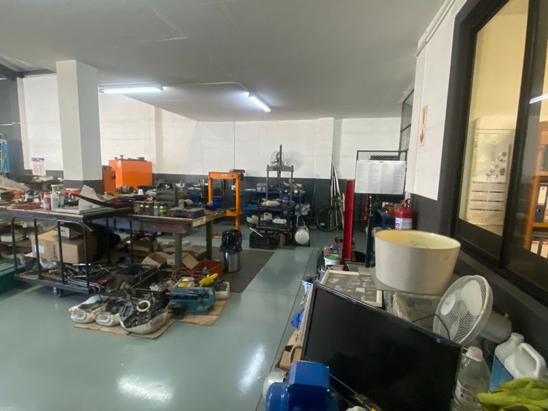 Industrial utility or workshop space featuring durable epoxy flooring, structural columns, and overhead fluorescent lighting, suitable for various commercial or industrial operations.