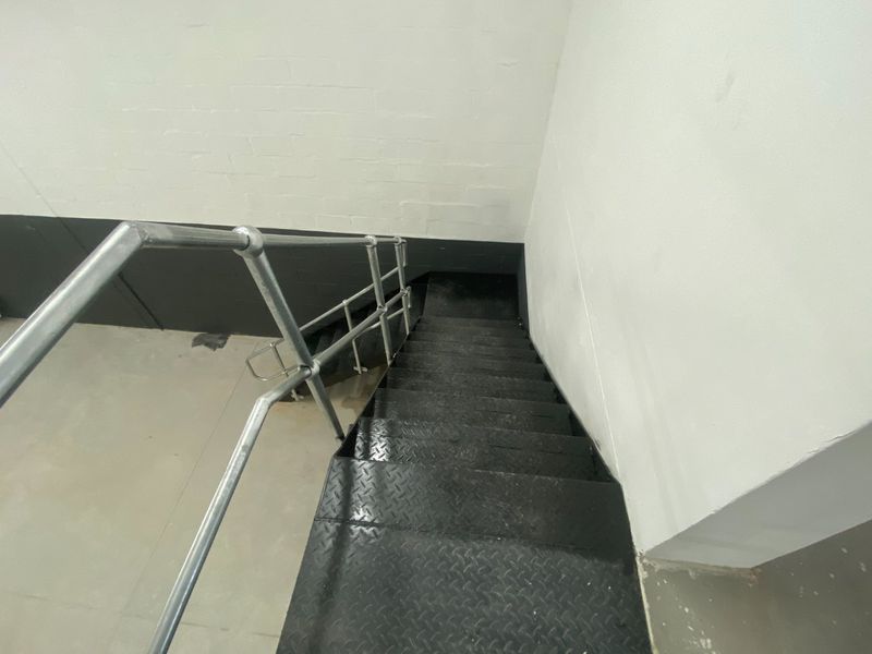 Industrial-style metal staircase with diamond plate treads and a galvanized steel handrail, providing access between levels in an industrial facility.