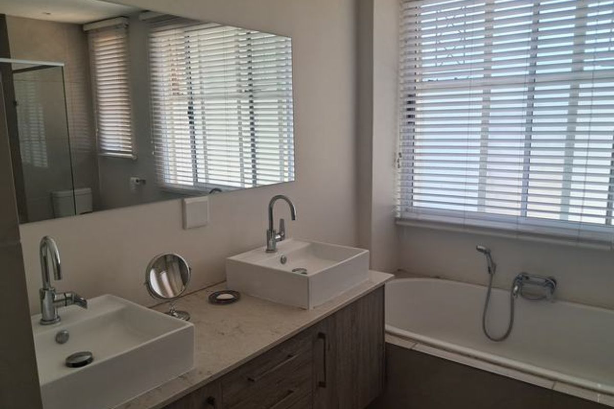 Modern bathroom featuring a double vanity with vessel sinks, stone countertop, and a built-in bathtub with a handheld shower attachment.