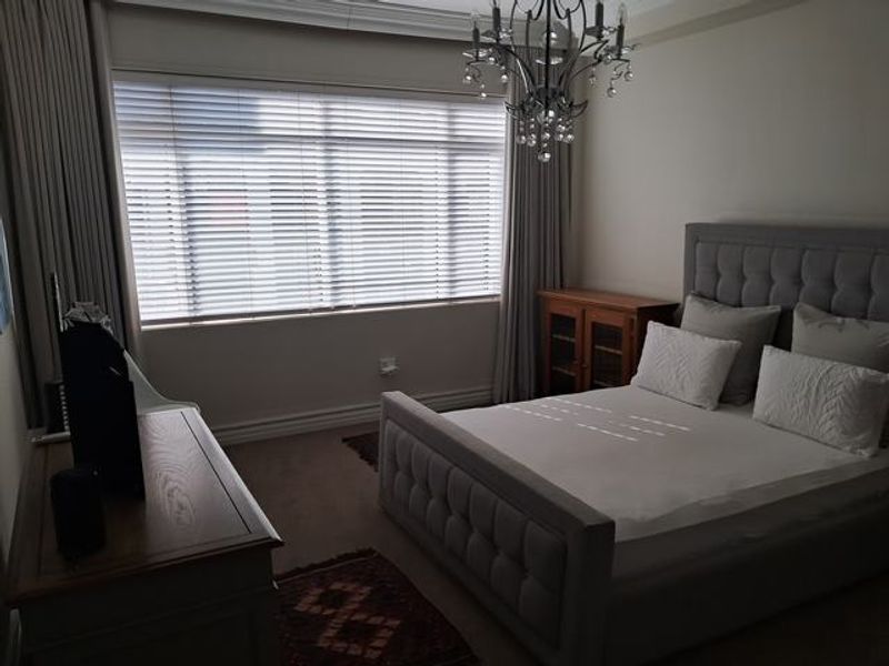 A well-maintained bedroom featuring crown molding, skirting boards, and venetian blinds, providing a neutral and comfortable living space.