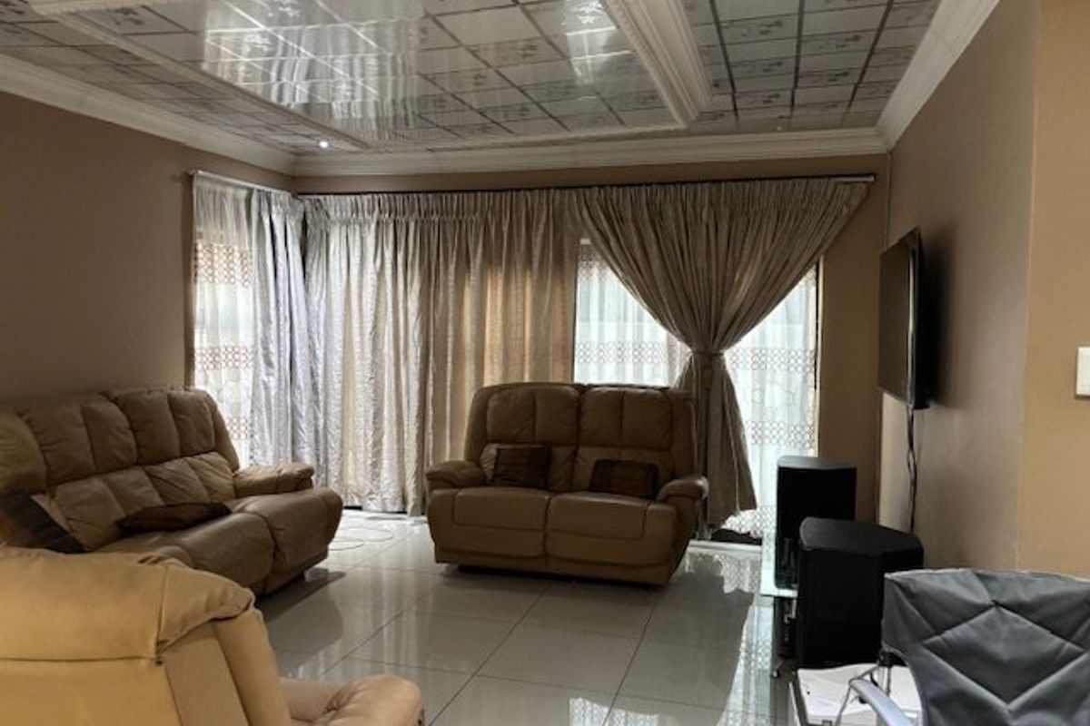 A living room featuring large format floor tiles and a decorative drop ceiling with recessed lighting.