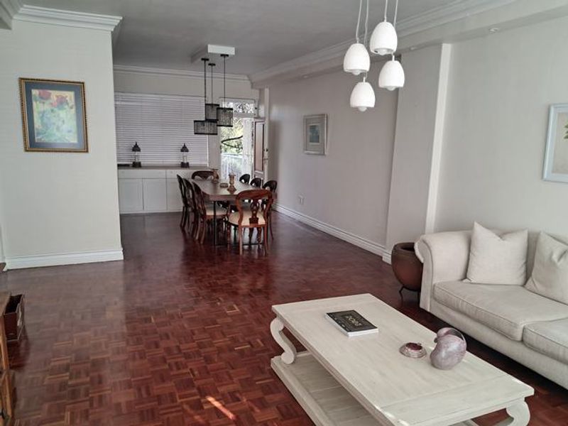 Spacious open-plan living and dining area featuring classic parquet flooring, elegant crown molding, and modern pendant lighting fixtures.