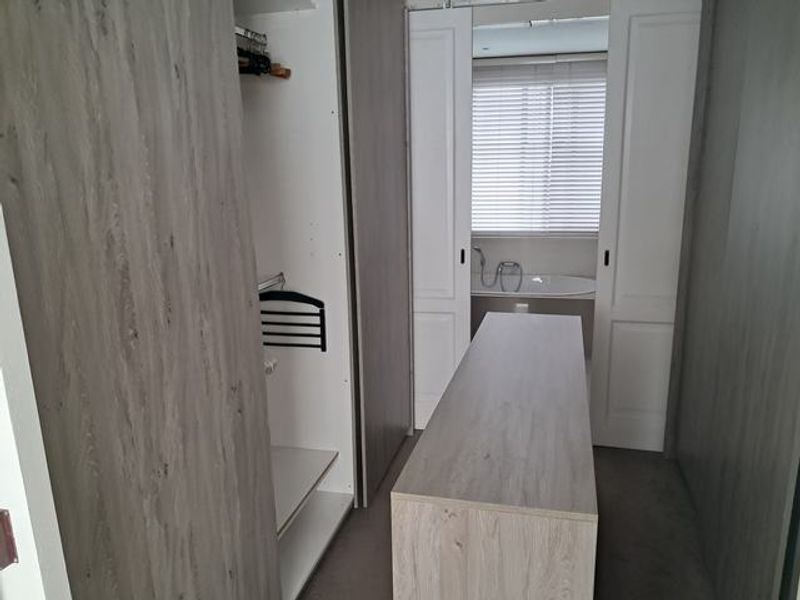 Walk-in dressing area featuring extensive built-in cabinetry, a central island unit, and direct access to an en-suite bathroom.