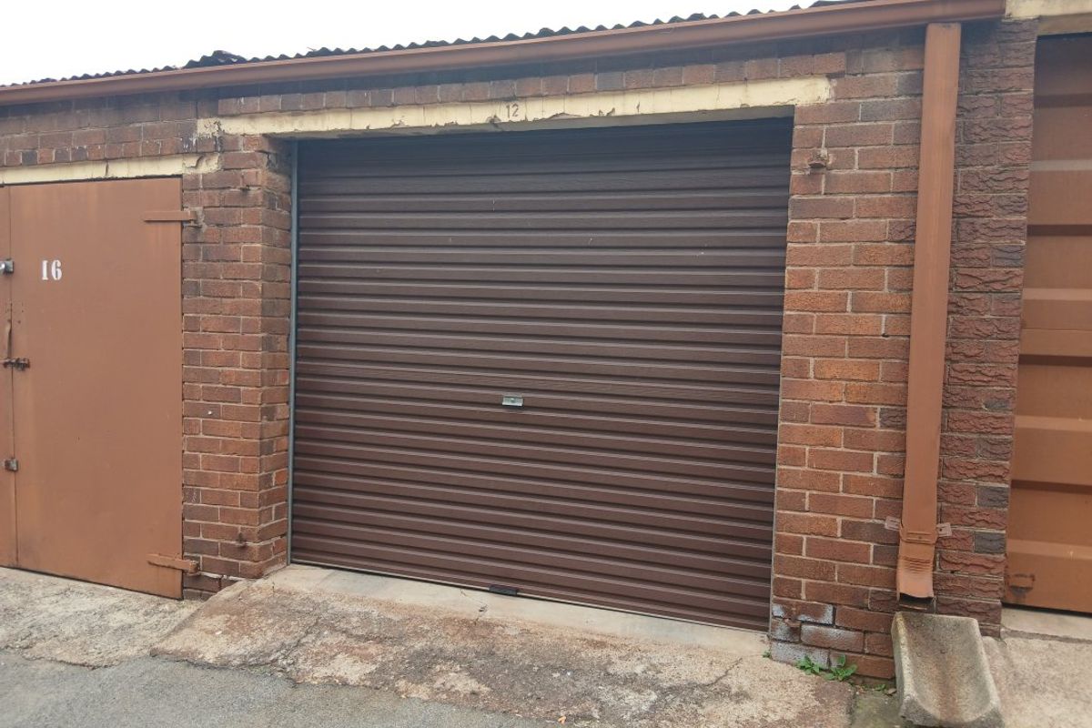 A single lock-up garage unit featuring a brown roller shutter door and brick exterior construction.