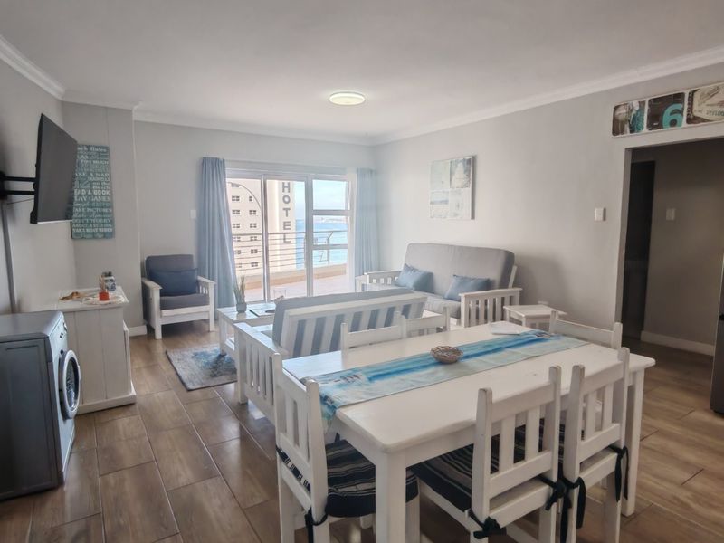 Open-plan living and dining area featuring tiled flooring, neutral walls, and direct access to a balcony with sea views.