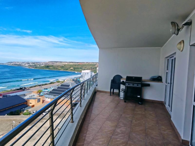 Spacious balcony featuring tiled flooring and a metal balustrade, offering expansive coastal and ocean views.