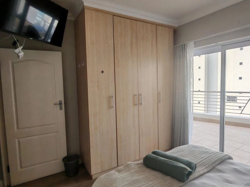 Bedroom featuring light wood-finish built-in wardrobes and a sliding glass door providing access to an outdoor balcony area.