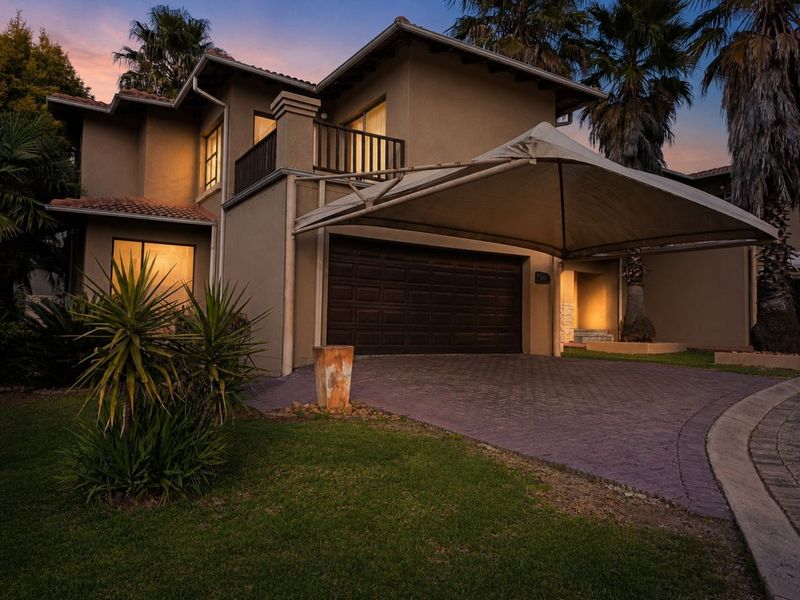 Front elevation of a two-story house featuring a paved driveway, double garage, and a shade sail carport at dusk.