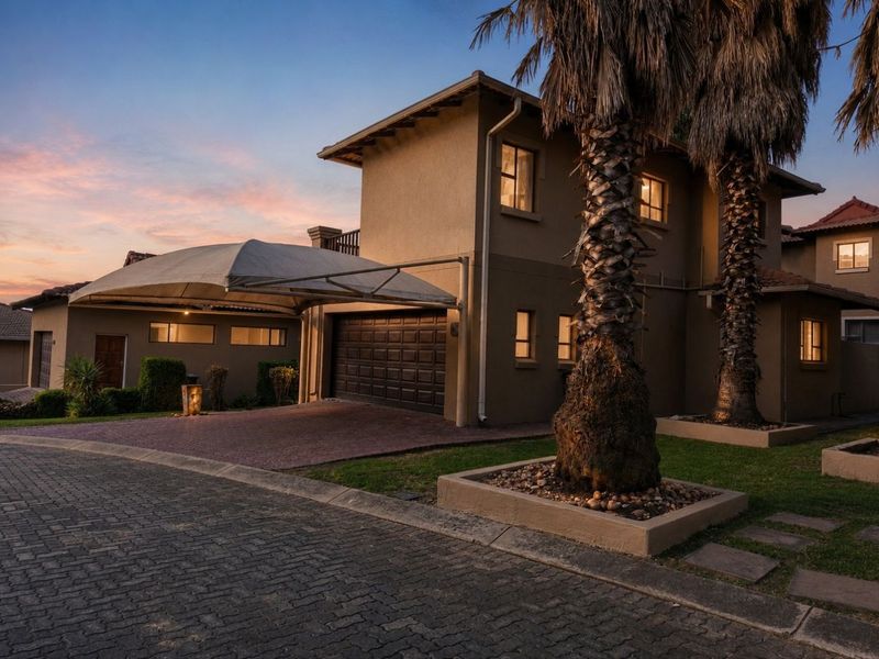 Front elevation of a two-story residence featuring a paved driveway, shade sail carport, and integrated garage, set in a well-maintained residential estate.
