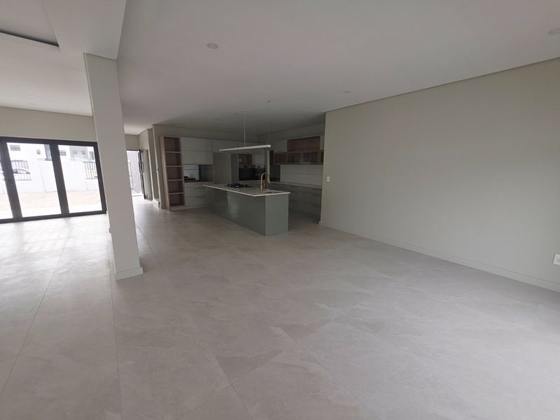 Spacious open-plan living area featuring a modern kitchen with a central island, built-in cabinetry, and large sliding glass doors leading to the exterior.