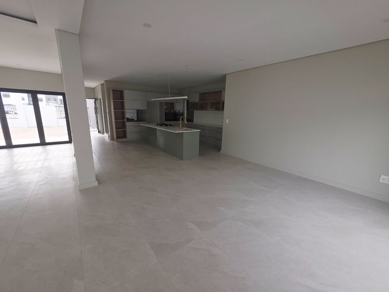Spacious open-plan living and kitchen area featuring modern cabinetry, a central island, tiled flooring, and large sliding doors leading to the exterior.