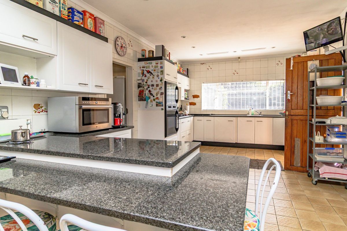 Spacious kitchen featuring granite countertops, ample cabinetry, built-in oven, and tiled finishes, offering a functional layout with potential for modern updates.