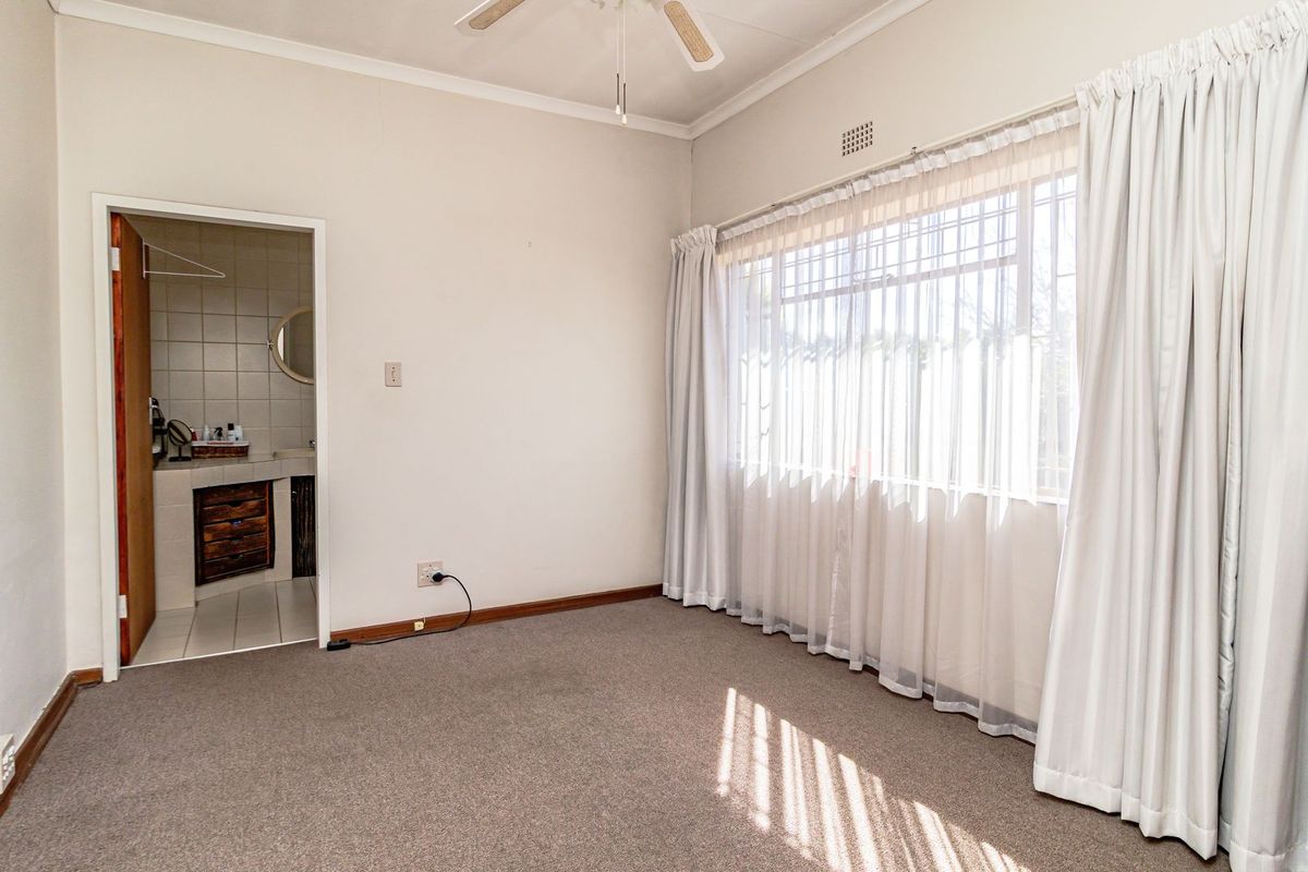 A spacious, empty bedroom featuring carpeted flooring, a ceiling fan, and direct access to an en-suite bathroom, offering a blank canvas for personalization.