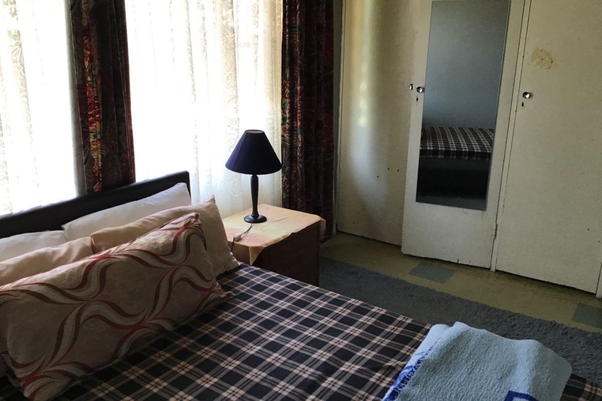 A bedroom featuring a built-in wardrobe with a mirrored door and large windows allowing natural light.