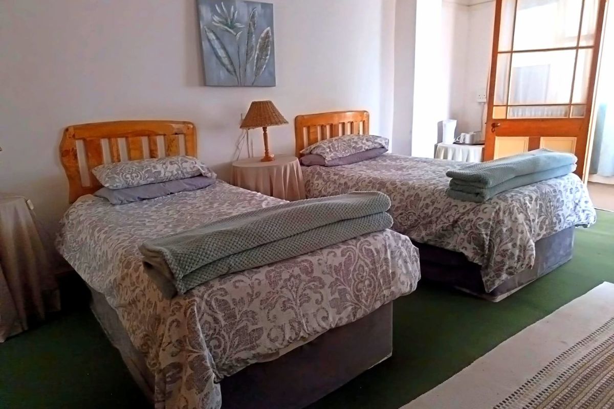 A bedroom featuring a timber-framed door with glass panels and carpeted flooring, offering a functional space in need of cosmetic updates.
