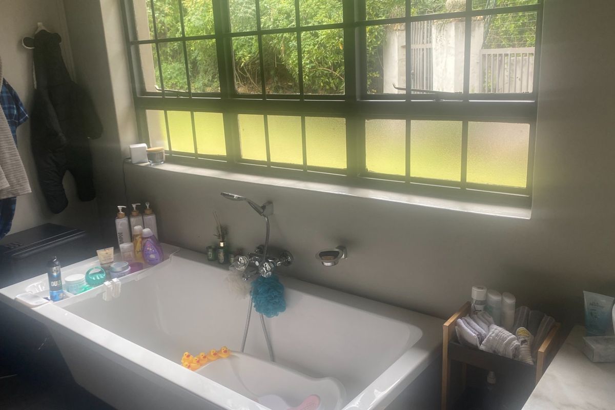 A bathroom featuring a built-in bathtub with wall-mounted fixtures and a large grid-pattern window providing natural light.