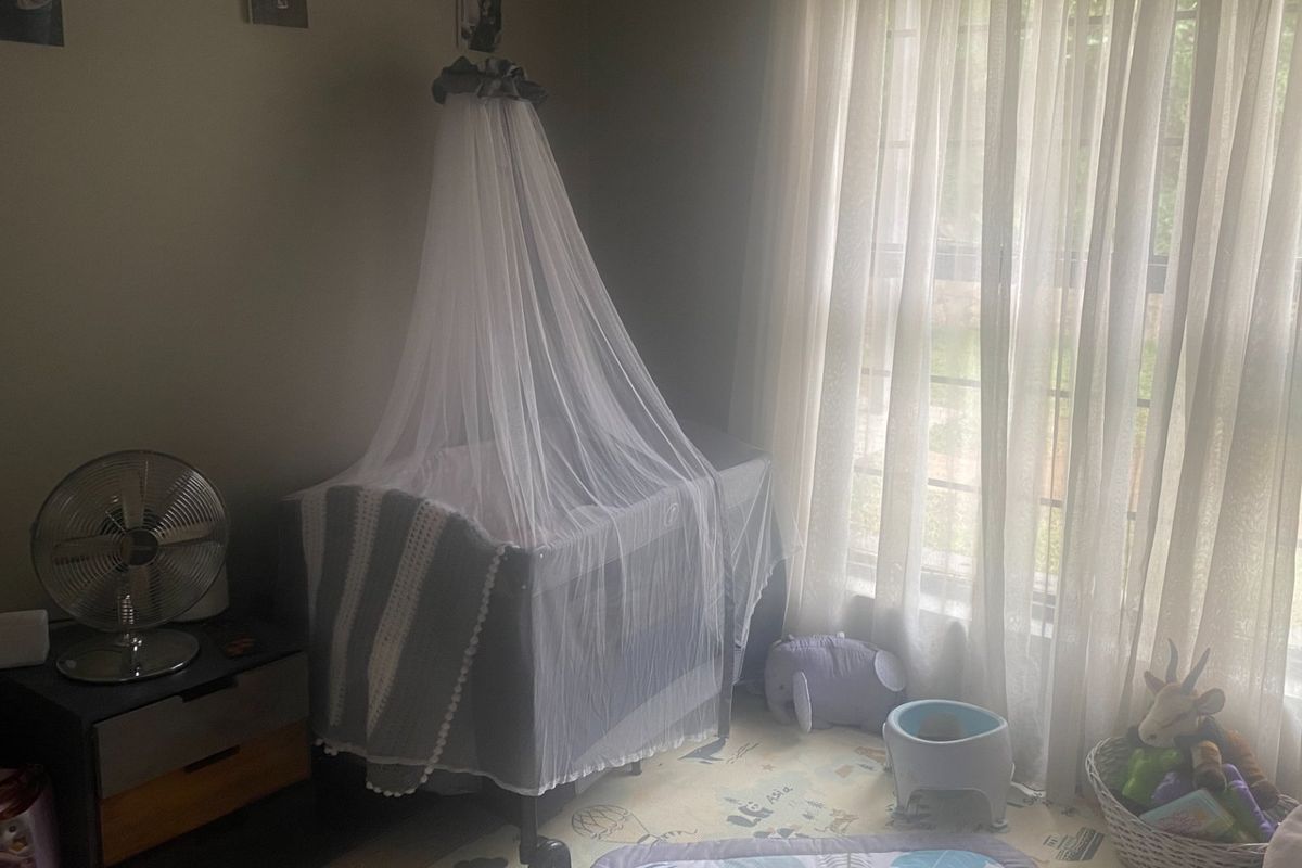 A bedroom featuring a large window with sheer curtains, providing natural light to the space.