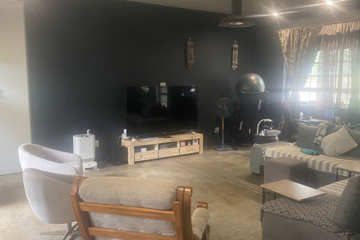 Spacious living room featuring polished concrete floors, dark accent walls, and recessed lighting, offering a contemporary industrial aesthetic.