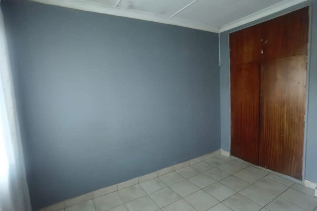 A vacant bedroom featuring tiled flooring and a built-in wooden wardrobe, offering a blank canvas for personalization.