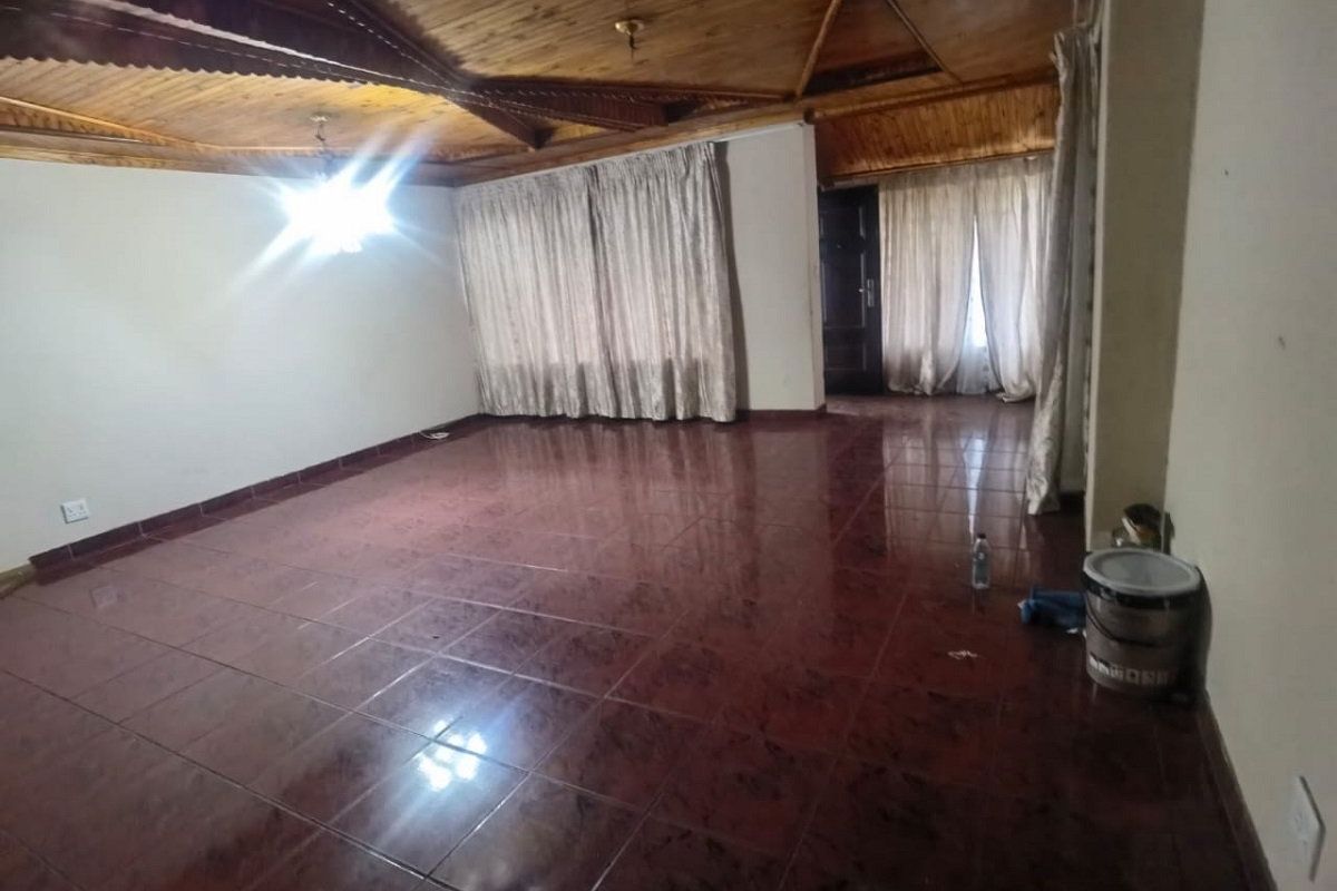 Spacious living area featuring a distinctive timber-clad vaulted ceiling and dark tiled flooring, offering a blank canvas for interior design.
