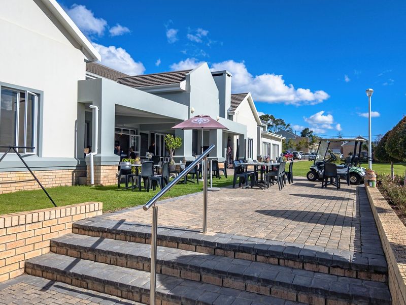 Spacious covered patio area featuring paved flooring, brick retaining walls, and stainless steel handrails, providing an ideal outdoor space for relaxation and entertainment.