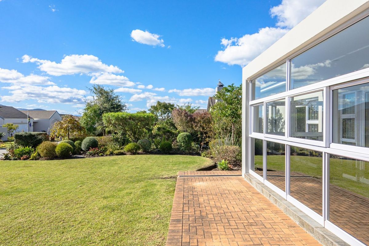 A well-maintained rear garden featuring a brick-paved patio and large glass sliding doors providing seamless indoor-outdoor flow.