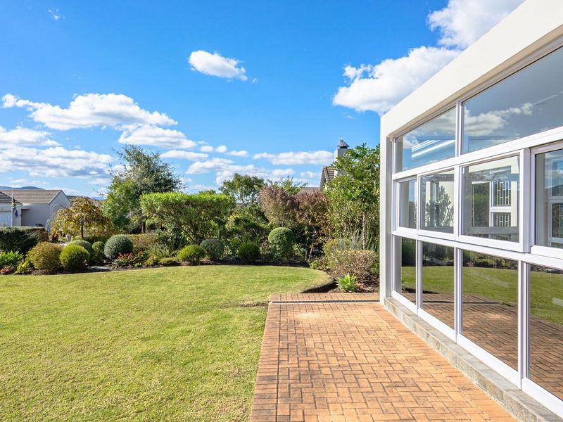 A well-maintained rear garden featuring a brick-paved patio and large glass sliding doors providing seamless indoor-outdoor flow.