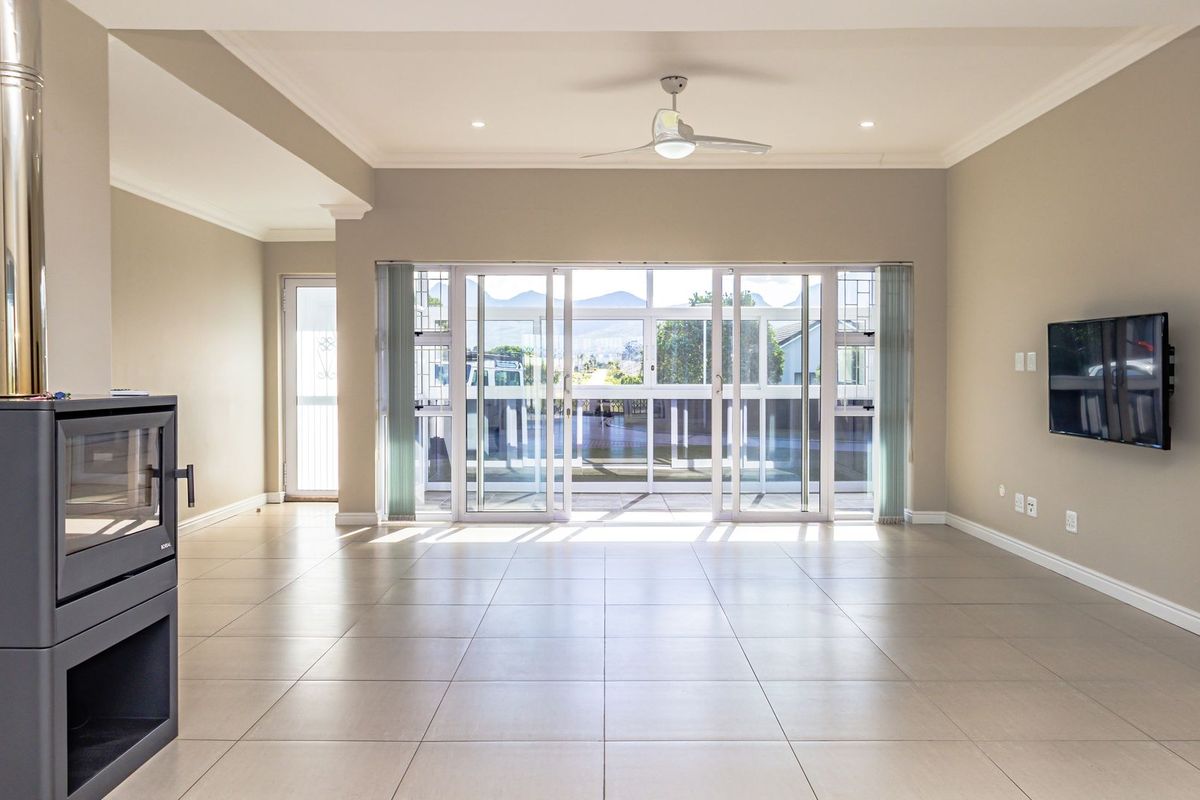 Spacious, light-filled living area featuring neutral tiled flooring, a modern freestanding fireplace, and large sliding glass doors opening to an outdoor space.