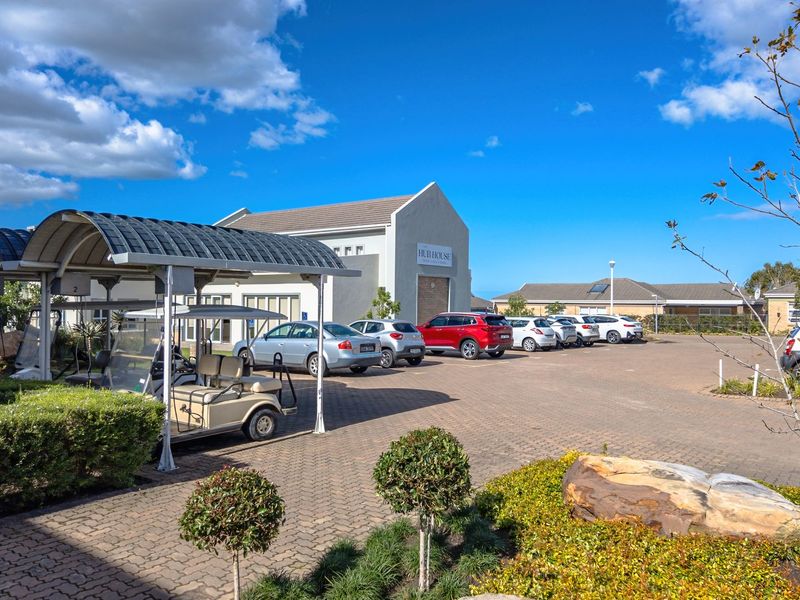 A well-maintained paved parking area featuring covered bays and landscaped garden beds in front of the property building.