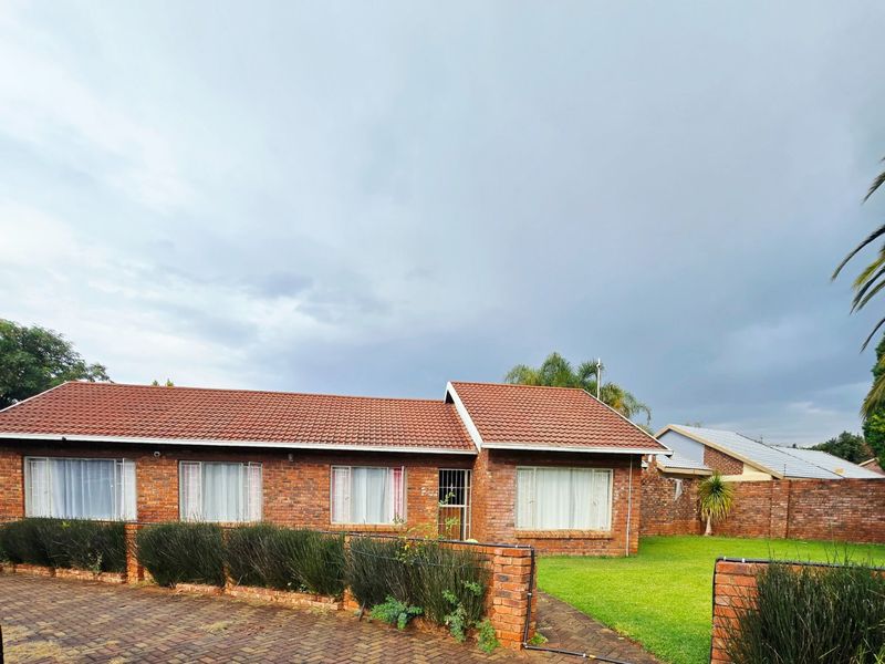 A single-story face brick house featuring a tiled roof, paved driveway, and a well-maintained front lawn with perimeter brick walling.