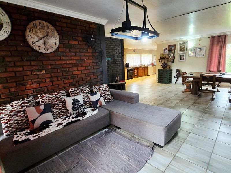 Spacious open-plan living and dining area featuring an exposed brick feature wall, ceramic tiled flooring, and modern pendant lighting.
