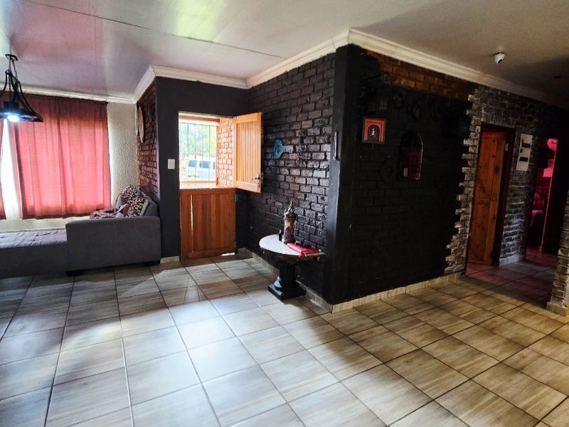 Living area featuring tiled flooring, exposed brick walls, and a traditional stable-style door leading to the exterior.