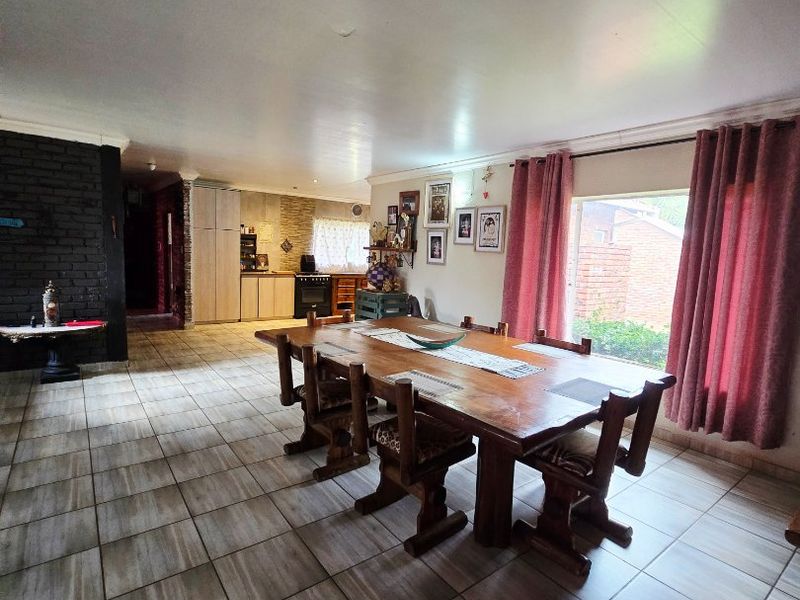 Spacious open-plan dining and kitchen area featuring tiled flooring, an exposed brick feature wall, and direct access to the kitchen workspace.