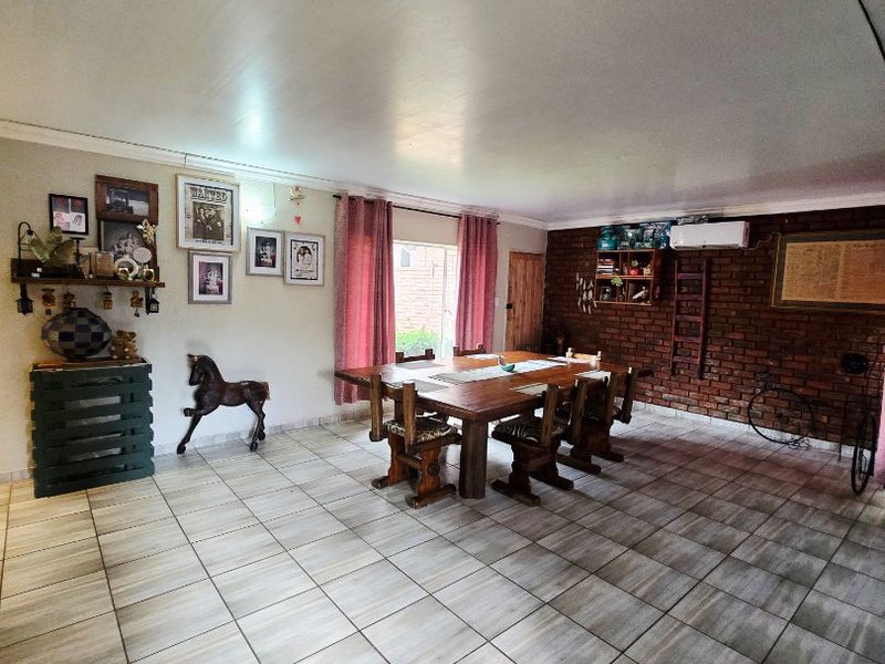 Spacious dining area featuring tiled flooring, an exposed brick feature wall, and a wall-mounted air conditioning unit.