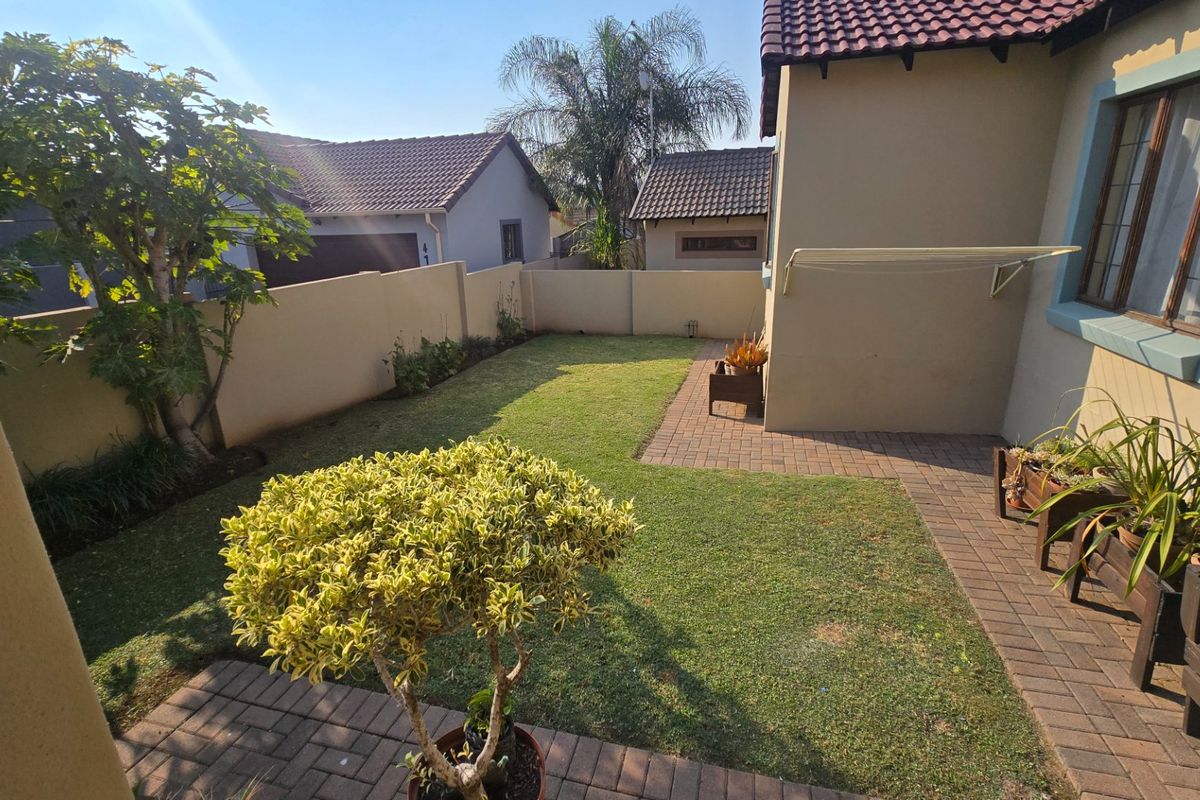 A private rear garden featuring a well-maintained lawn, paved pathways, and perimeter boundary walls, providing a functional outdoor space.