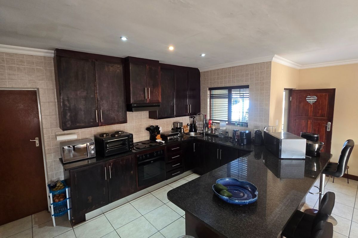 A functional kitchen featuring dark wood cabinetry, granite countertops, a built-in oven, and a breakfast bar island with tiled flooring throughout.