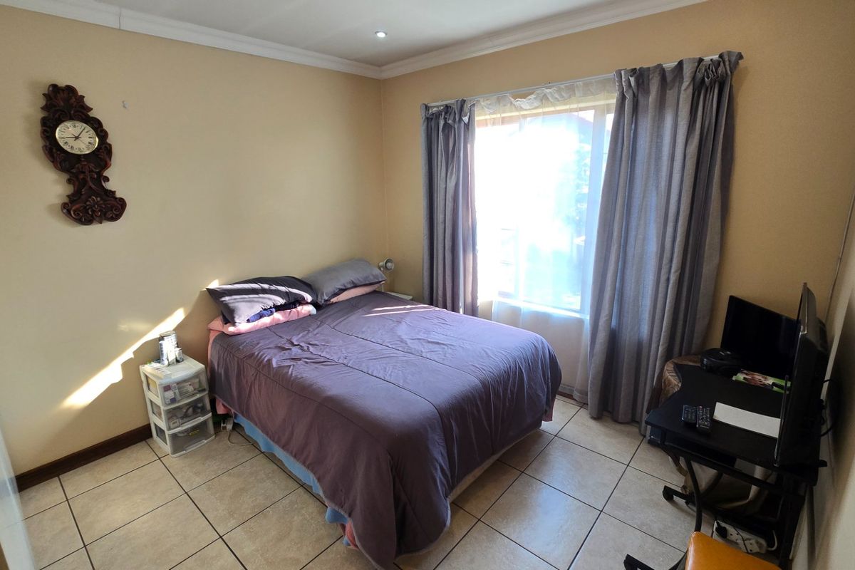 A functional bedroom featuring tiled flooring, a built-in cupboard, and coving, offering a neutral base for personalization.