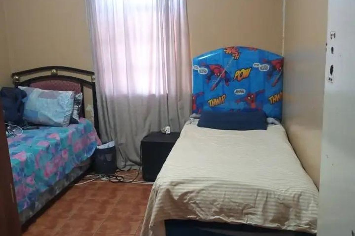 A bedroom featuring tiled flooring and decorative ceiling cornicing, currently requiring cosmetic updates to the wall and ceiling finishes.