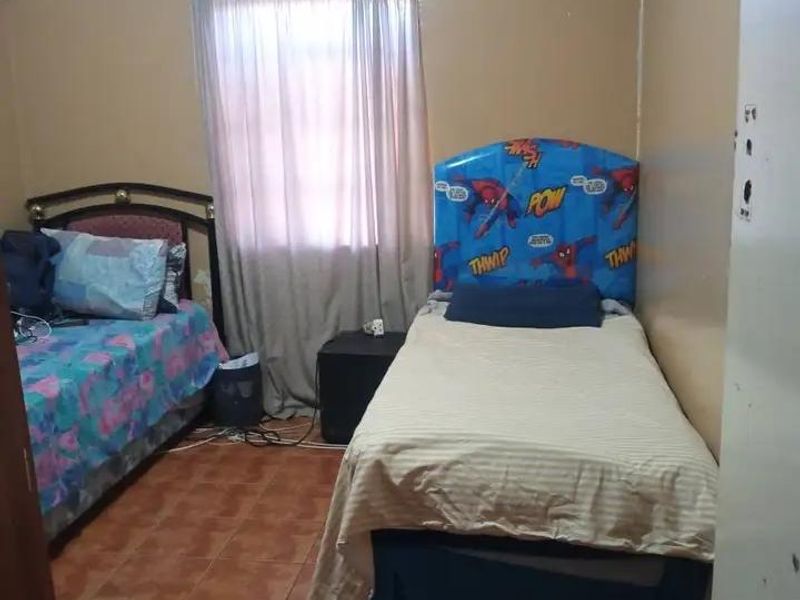 A bedroom featuring tiled flooring and decorative ceiling cornicing, currently requiring cosmetic updates to the wall and ceiling finishes.