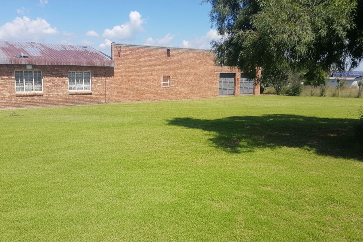 A view of the rear exterior of the property featuring a large lawn, brick facade, and metal roofing.