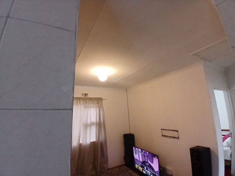 A living room area featuring standard ceiling cornicing and a central light fixture, with a visible wall mounting point.