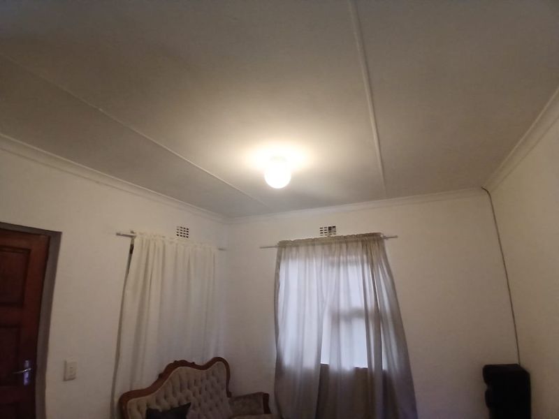 A simple bedroom interior featuring standard ceiling cornices and wall-mounted ventilation grilles.
