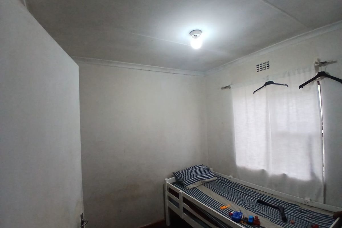 A compact bedroom featuring plain walls, a ventilation grille, and coving, requiring cosmetic updates to improve its overall condition and appeal.